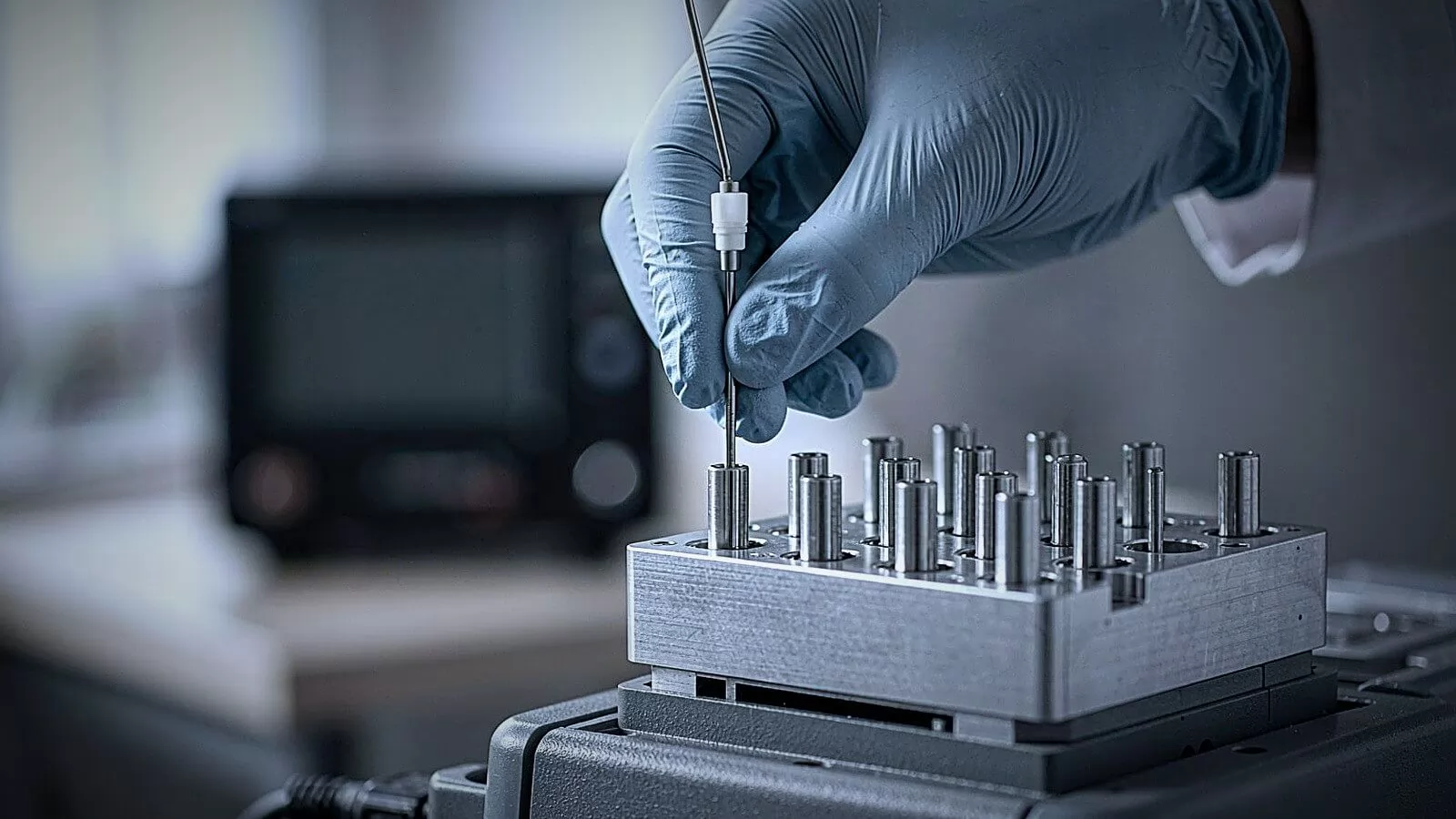Technician guiding a temperature probe into the drilled bores of a dry block calibrator insert
